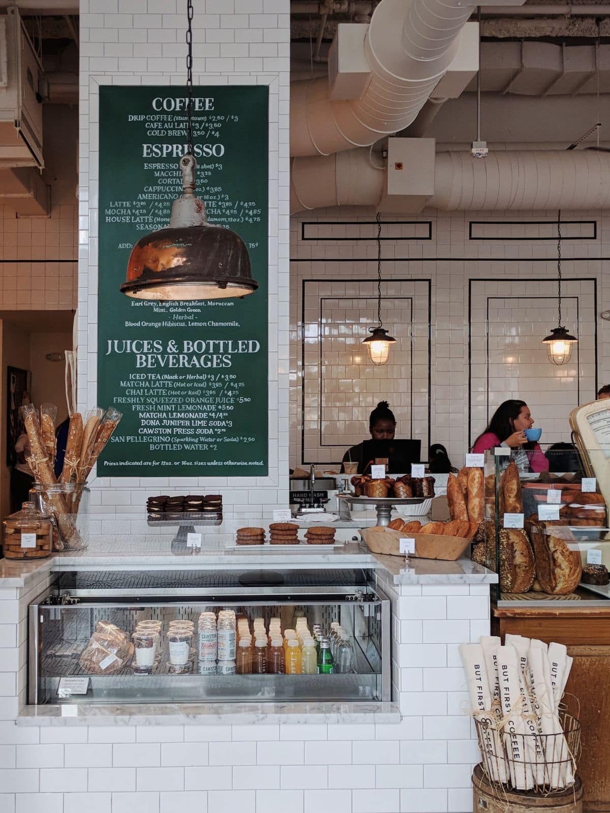 Tatte Bakery counter with baguettes, pastries, and hanging lamps