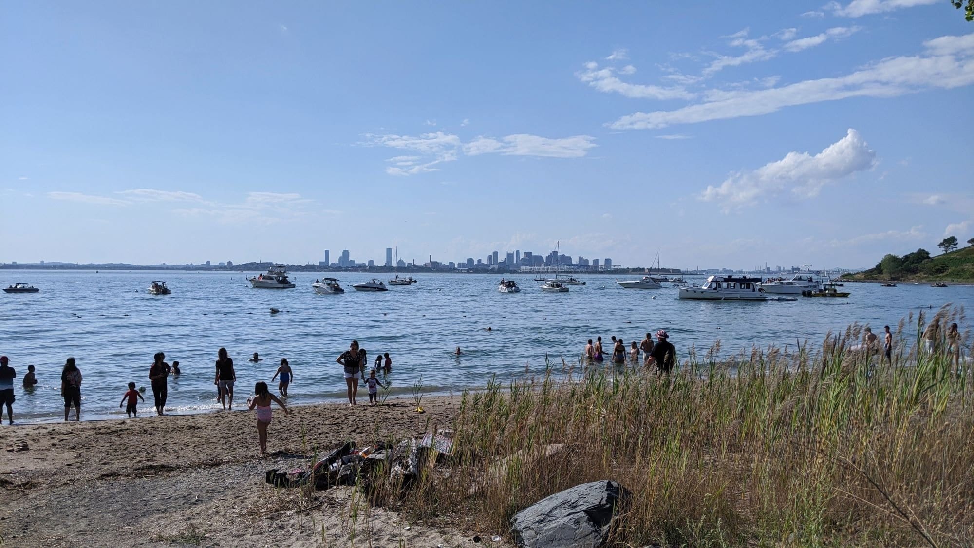 Spectacle Island beach with boats and the Boston skyline in the distance